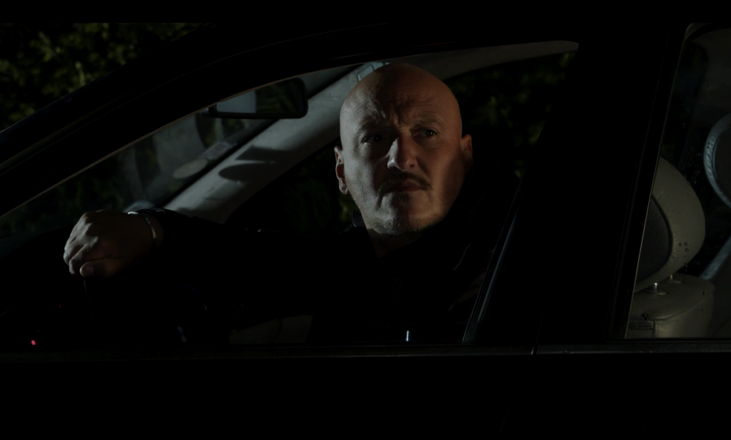 Photo d'un homme regardant à travers la vitre du siège conducteur de sa voiture la nuit.