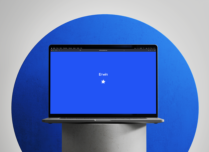 Mockup d'un ordinateur disposé sur un support, affichant la page d'accueil d'un site, avec écrit "Erwin" au centre accompagné d'un logo de fleur blanche.